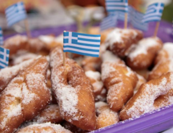 Plate of greek baked goods with small greek flag toothpicks stuck in them