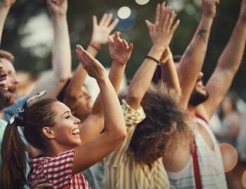 young people dancing at outdoor concert in summer