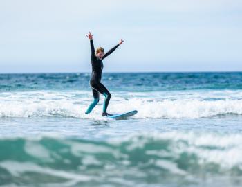 Woman on surf board with her hands up